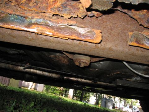 1991 Ford LTD Crown Victoria - The undercarriage shows significant rust and deterioration, with some metal pieces flaking off.