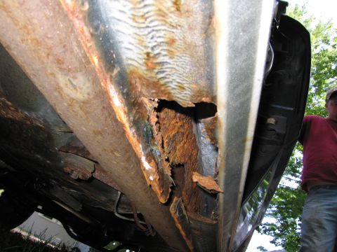 1991 Ford LTD Crown Victoria - Severe rust damage is visible on the rocker panel and undercarriage of this vehicle, indicating significant structural compromise.