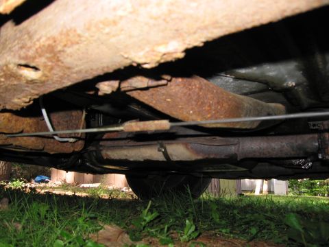 1991 Ford LTD Crown Victoria - Heavily rusted undercarriage of a vehicle, showing frame and exhaust components.