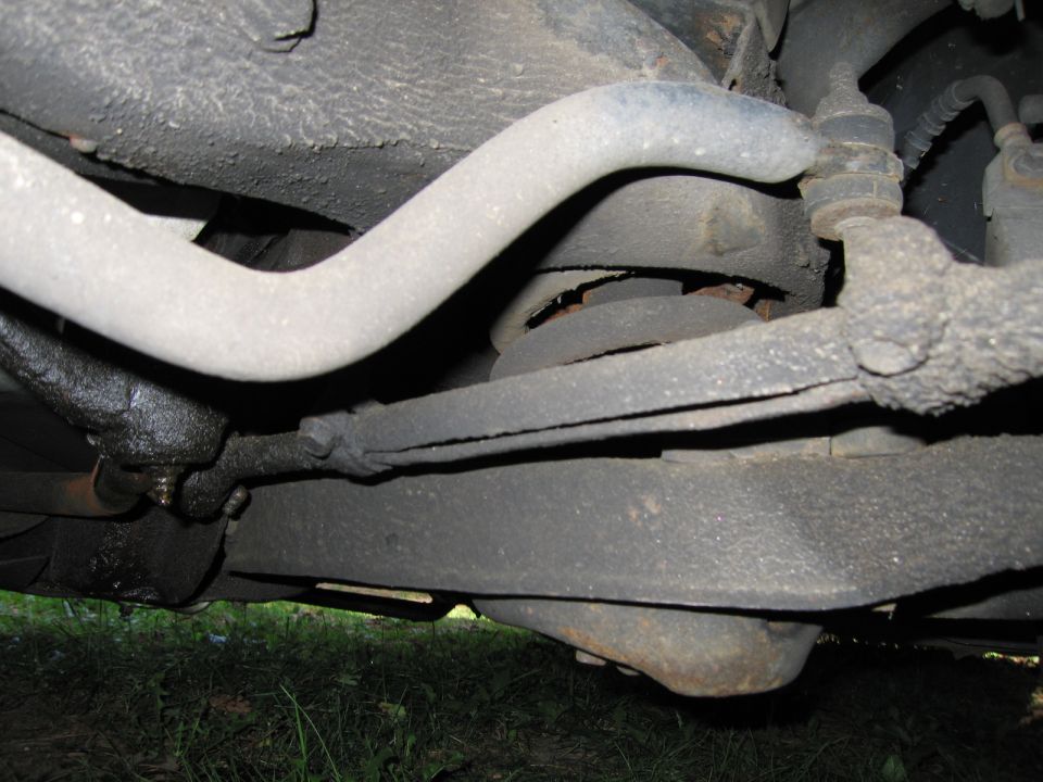 Underside view of car suspension parts, including sway bar and control arms. Some grease visible