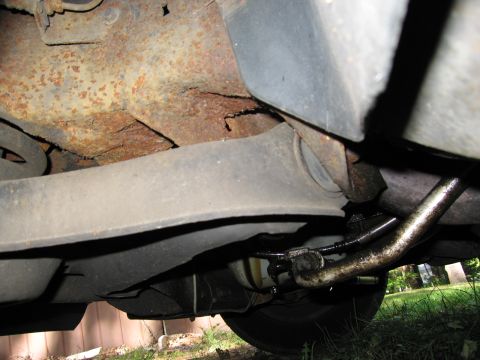 1991 Ford LTD Crown Victoria - The underside of a vehicle shows significant rust and wear on its suspension and frame components.