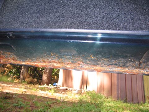 1991 Ford LTD Crown Victoria - The lower door sill of a dark green vehicle shows significant rust damage.