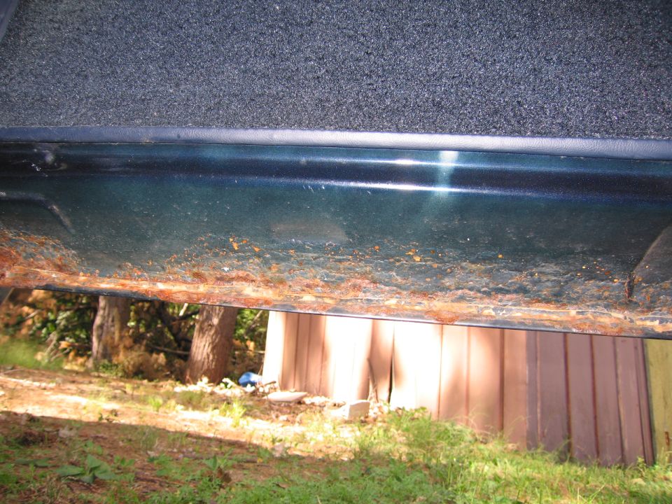Rusted car door sill, dark green paint