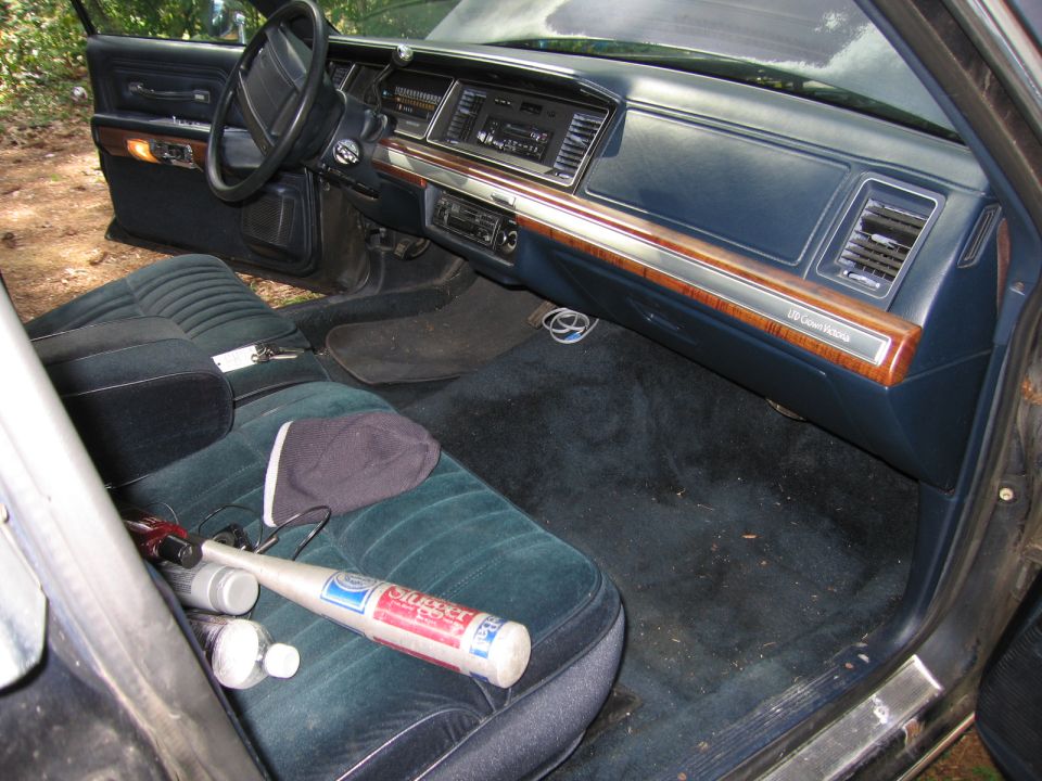 1991 Ford Crown Victoria LTD interior showing dashboard, steering wheel, and seats. A baseball bat is on the passenger seat