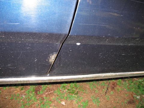 1991 Ford LTD Crown Victoria - Detail shot of a car's door seam and lower body panel, showing wear and dirt.