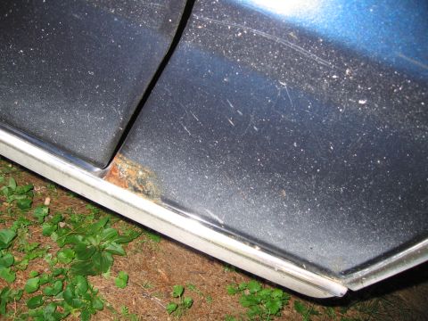 1991 Ford LTD Crown Victoria - The bottom edge of a car door shows signs of rust and wear, with blue paint above.