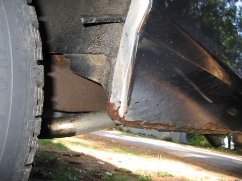 1991 Ford LTD Crown Victoria - Rust is visible on the lower rear fender and wheel well of a vehicle, with a tire and exhaust pipe in view.