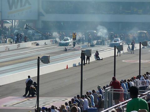 1992 Ford Mustang - Drag cars prepare for a race, with spectators in the stands and a large WIX Filters banner overhead.