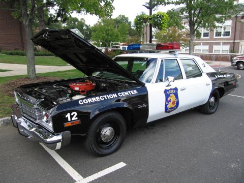 1991 Ford LTD Crown Victoria - black and white vintage four-door 'Correction Center' sedan, Essex number 12, with hood raised and roof lights, parked at a show.