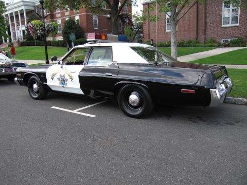 1991 Ford LTD Crown Victoria - black-and-white Highway Patrol sedan with a gold star door shield and roof beacons parked at a curb.