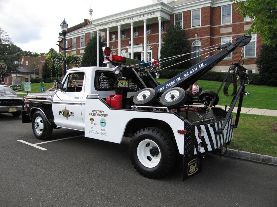 Black and white Ford police tow truck with boom and POLICE lettering, rear view