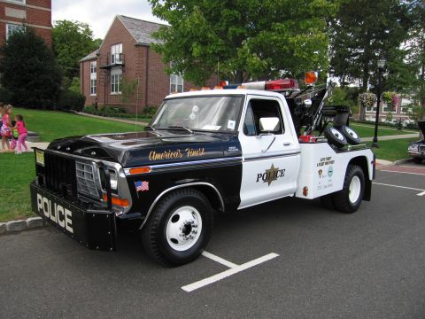 1991 Ford LTD Crown Victoria - black-and-white Ford police wrecker with POLICE on the front bumper, a star door decal and a boom on the bed.