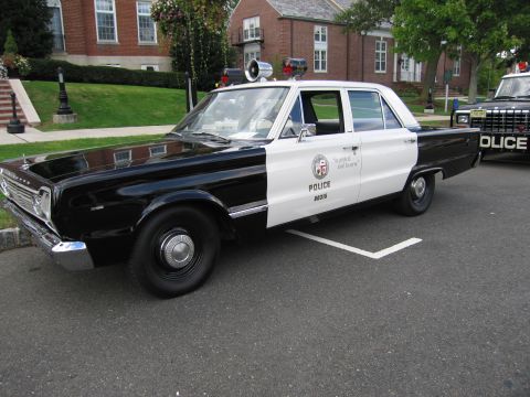 1991 Ford LTD Crown Victoria - black-and-white police sedan marked POLICE To Protect and Serve with a fender spotlight and roof beacon.