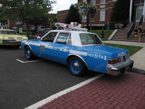 1991 Ford LTD Crown Victoria - blue-and-white police sedan numbered 2840 with HWY lettering, blue wheels and a roof light bar at a brick curb.