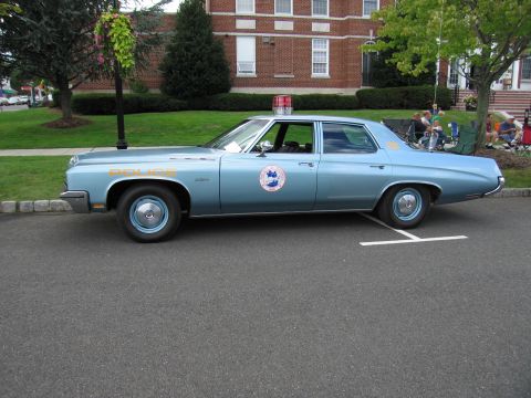 1991 Ford LTD Crown Victoria - Side profile of a light blue full-size police sedan with POLICE lettering and a round door seal at a curb.