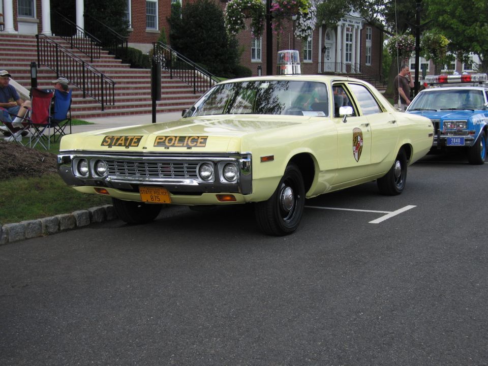 Pale yellow Dodge STATE POLICE sedan with hood lettering, front three-quarter view
