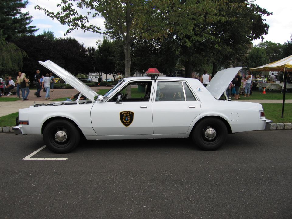 White police sedan with open hood and trunk, side profile view