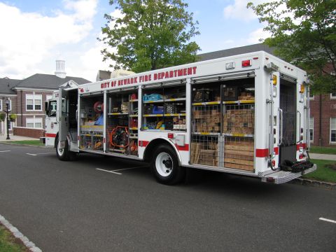 1991 Ford LTD Crown Victoria - white 'City of Newark Fire Department' rescue truck with open side compartments displaying equipment, parked outdoors.