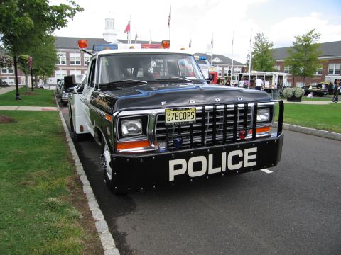 1991 Ford LTD Crown Victoria - black-and-white Ford pickup lettered 'POLICE' with a brush guard, roof beacons and a '78COPS' plate at a car show.