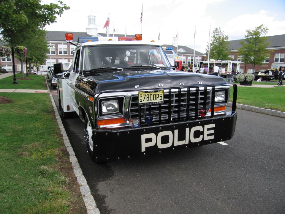 Black and white Ford pickup marked POLICE, front view with push bar and lights