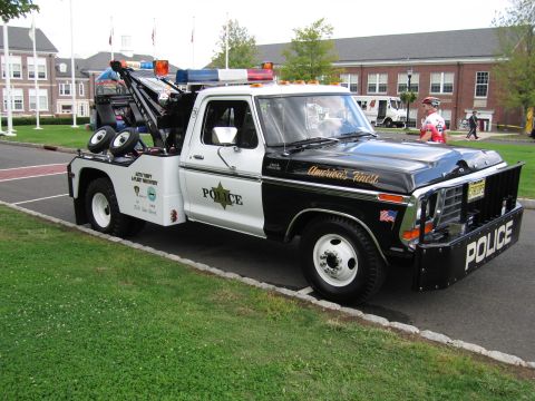 1991 Ford LTD Crown Victoria - black-and-white Ford tow truck lettered 'POLICE' and 'America's Finest' with a recovery boom and roof lights.