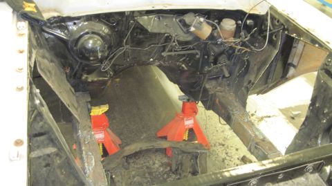 1992 Ford Mustang - The engine bay of a 1964 Ford Fairlane is shown on jack stands, with the engine removed and frame rails exposed.