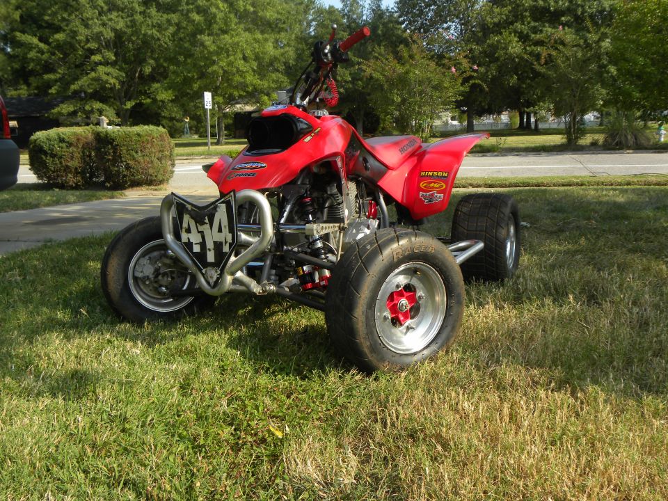 Red sport ATV quad with number 414 plate parked on grass