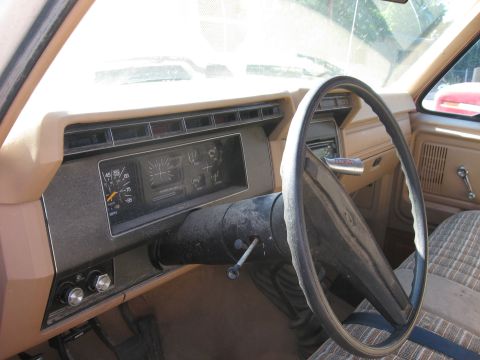 1981 Ford Bronco - The interior of a 1981 Ford Bronco shows its dashboard, steering wheel, and plaid seat upholstery.