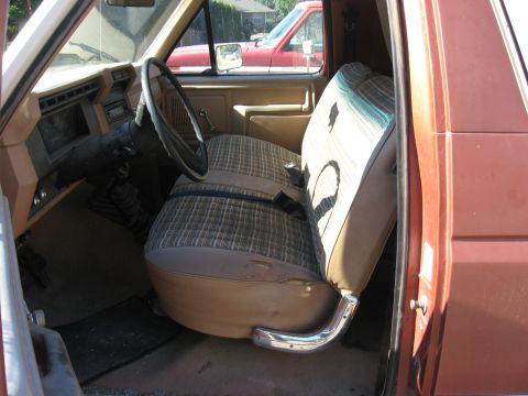 1981 Ford Bronco - Interior view of a 1981 Ford Bronco, with a red truck seen through the passenger window.