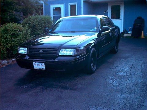 2000 Ford Crown Victoria - A black sedan is parked in front of a blue house. The vehicle's front end is facing the camera.
