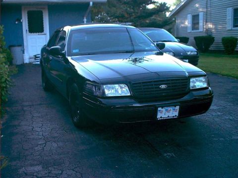 2000 Ford Crown Victoria - A black 2000 Ford Crown Victoria is parked in a driveway with another vehicle behind it.