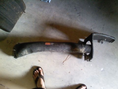1990 Ford Bronco - An automotive part is shown on a concrete floor, with a foot in a sandal nearby.