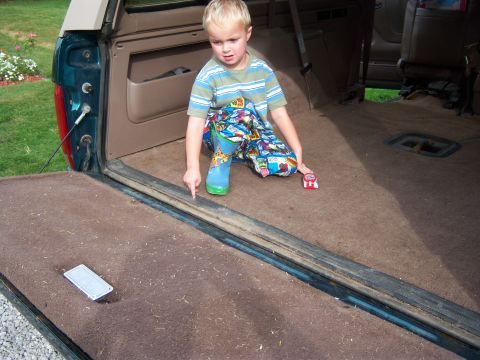 1996 Ford Bronco - Child points at the cargo area floor of a vehicle, with a toy car nearby.
