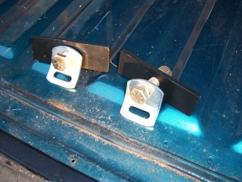 1996 Ford Bronco - Two metal child seat tether anchors are shown bolted to a teal surface with visible rust and wear.