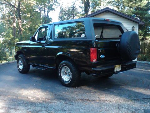 1996 Ford Bronco - Rear view of a black 1996 Ford Bronco parked in a driveway next to a garage.