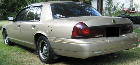2000 Mercury Grand Marquis - Rear view of a gold 2000 Mercury Grand Marquis sedan parked outdoors on a grassy area.