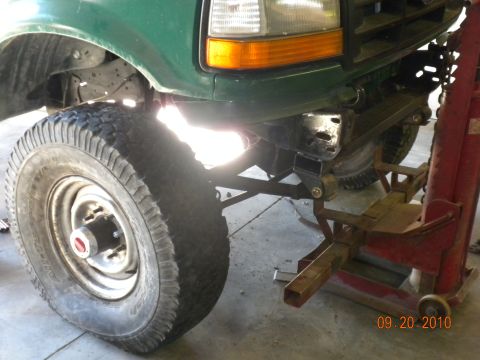 1989 Ford Bronco - Front end of a green Ford F-Series truck, possibly undergoing modifications, with a jack stand supporting the frame.