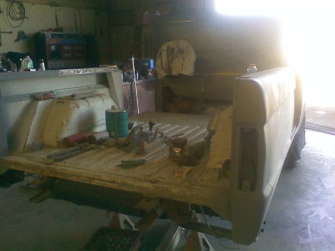 1966 Ford Bronco - The rear bed of a 1966 Ford Bronco is visible, showing some tools and a green can, suggesting it is undergoing restoration.