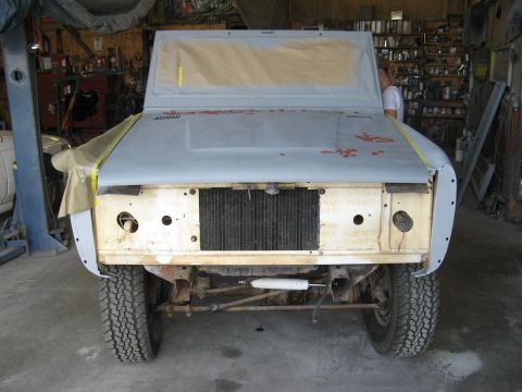 1966 Ford Bronco - A 1966 Ford Bronco is undergoing bodywork in a garage, showing its front end with primer and taped-off windows.