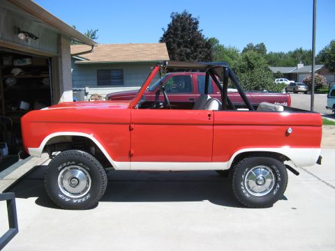 1966 Ford Bronco - A red and white 1966 Ford Bronco is parked in a driveway next to a red pickup truck.