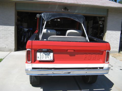 1966 Ford Bronco - The rear of a red 1966 Ford Bronco is shown parked in front of an open garage.