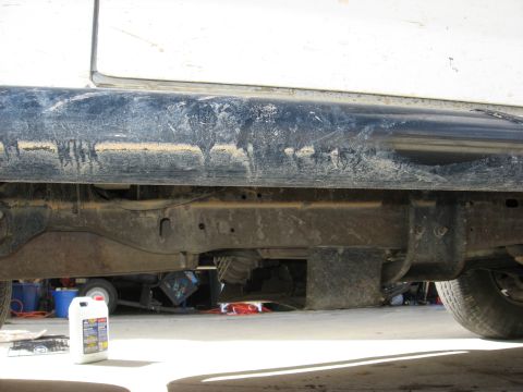 1994 Ford Bronco - The underside of a vehicle is shown, with a bottle of automotive fluid nearby.
