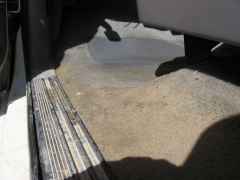 1994 Ford Bronco - The interior floor of the vehicle shows signs of wear and tear, with dirty carpeting and a metal step plate visible.