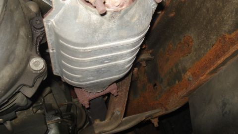 1988 Ford Bronco - Underside view of a vehicle's exhaust system, focusing on a catalytic converter and frame rust.