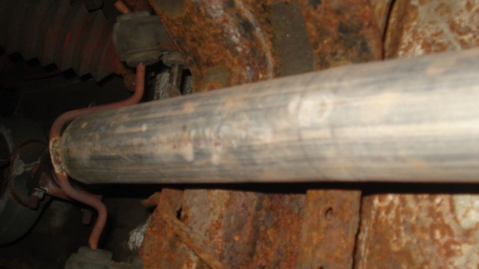 Exhaust pipe with red hangers attached to rusty frame components