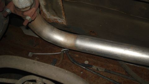 1988 Ford Bronco - The underside of a vehicle shows a section of the exhaust system, including a clamp and piping.