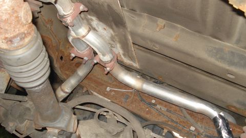 1988 Ford Bronco - The exhaust system and driveshaft are visible from underneath the vehicle, showing signs of rust.
