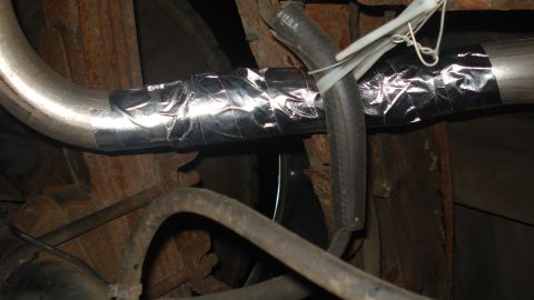 1988 Ford Bronco - A close-up view of a vehicle's exhaust pipe that has been repaired with silver tape and secured with zip ties.
