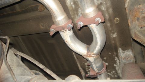 1988 Ford Bronco - The underside of a vehicle shows a Y-pipe exhaust system with visible rust on the flanges and bolts.