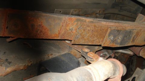 1988 Ford Bronco - Close-up view of heavily rusted frame components and exhaust system parts.